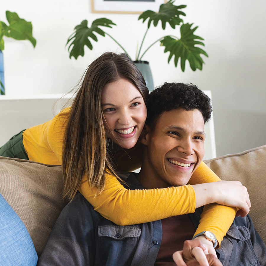 happy diverse couple sitting on couch and embracin 2023 12 01 20 31 29 utc